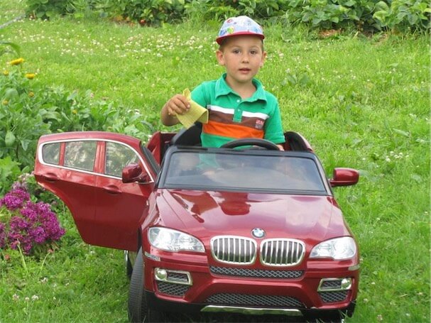 ребенок на детском автомобиле на аккумуляторе бмв красного цвета