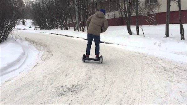 Молодой человек едет на 10 ти дюймовом гироскутере по снегу